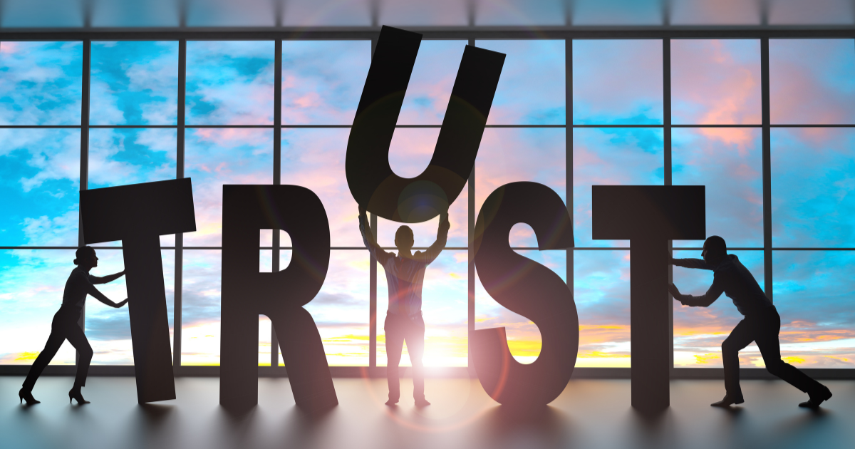 「TRUST（信頼）」の巨大な文字を複数の人物が協力して支えているイメージ。アクセスを単なる訪問者で終わらせず、本物の信頼を構築することが、成約（CV）への鍵であることを視覚的に表現。